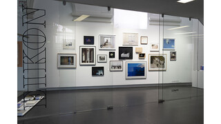 Fotoarbeiten auf einer weißen Wand hinter Glasscheibe