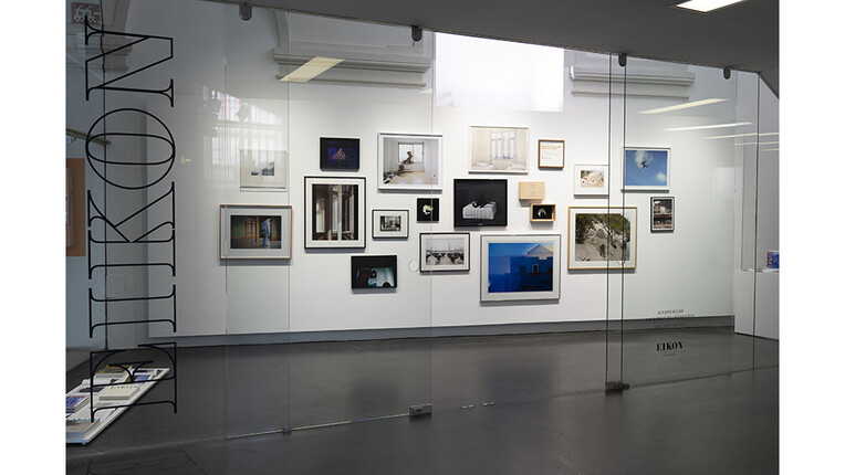 Fotoarbeiten auf einer weißen Wand hinter Glasscheibe