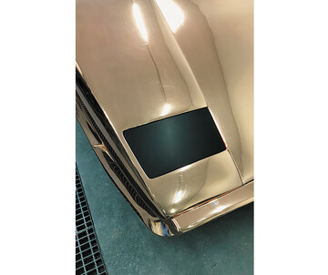 Detailaufnahme eines golden glänzenden Lamborghini auf grünem Untergrund