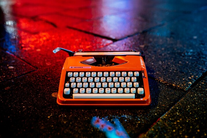 Red Hermes Baby typewriter on a wet road