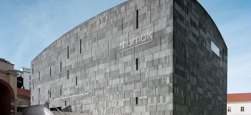 Cubic museum with a facade made of rectangular stone slabs and the inscription 'mumok'