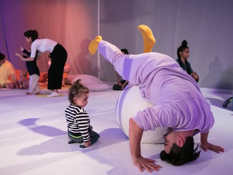 Das Foto zeigt Künstler:innen, die ganz junge Kinder dazu einladen, die Objekte auf der Bühne zu berühren und mit ihnen zu spielen.