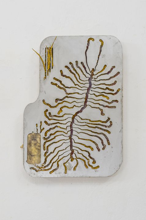 Rectangular object with rounded corners featuring gold-colored branching circuit paths on a white background mounted on a wall.