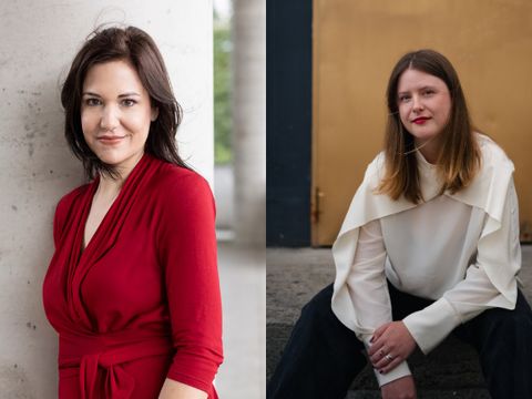 Zwei Frauen, eine steht in rotem Kleid an einer Säule, die andere sitzt in weißem Oberteil vor einer braunen Tür.