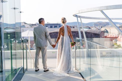 Wedding ceremony at MQ Libelle, MuseumsQuartier Vienna. A couple in wedding attire stands on the roof terrace and looks out over the rooftops of Vienna.