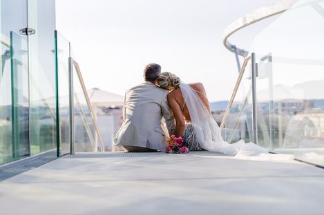 Wedding ceremony at MQ Libelle, MuseumsQuartier Vienna. A couple in wedding attire sits on the steps of MQ Libelle and gazes out over the rooftops of Vienna.