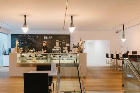 Staff member behind the counter at the mumok café, with view of seating area and bar.