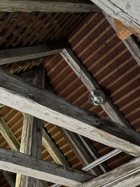 Close-up of a roof truss with wooden beams and a disco ball.