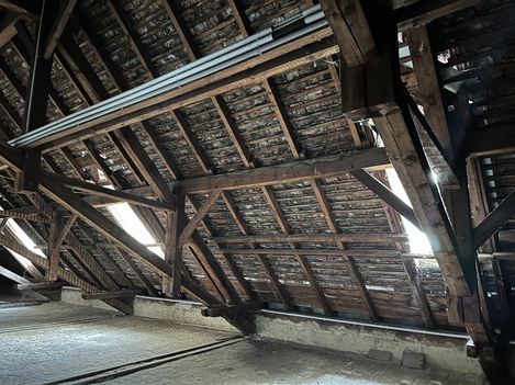 Historic roof truss with wooden beams and tile roofing.