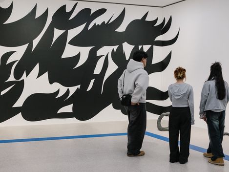 Menschen betrachten eine großflächige schwarz-weiße Wandkunst im mumok.