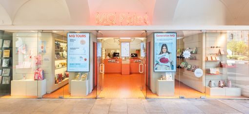 Verkaufsregal im MQ Point mit illustrierten Tassen, Büchern, Postkarten und Designprodukten.