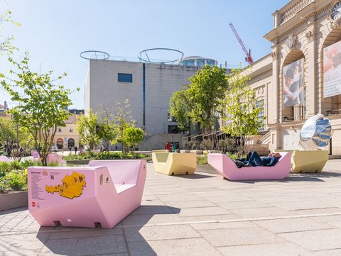 Mehrere Enzis im MuseumsQuartier Hof, Menschen entspannen darauf; im Hintergrund Museumsgebäude und Bäume.