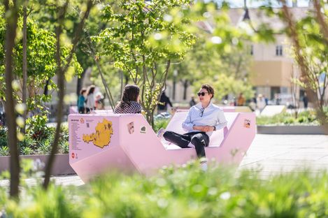 Zwei Personen sitzen sich auf einem rosa Enzi gegenüber und unterhalten sich im MuseumsQuartier Hof.