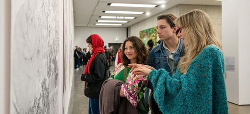 Three people are looking at a painting.