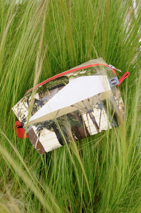 Transparente Tasche mit rotem Reißverschluss liegt in hohem Gras