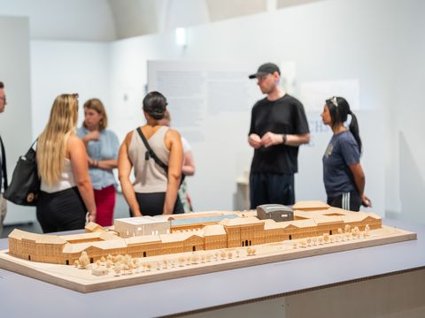 Gruppe von sechs Personen steht vor einem Architekturmodell in einem Ausstellungsraum