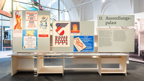 Ausstellungstafeln mit historischen Plakaten und Texten in einem hellen Ausstellungsraum mit hohen Fenstern