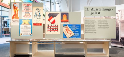 Ausstellungstafeln mit historischen Plakaten und Texten in einem hellen Ausstellungsraum mit hohen Fenstern