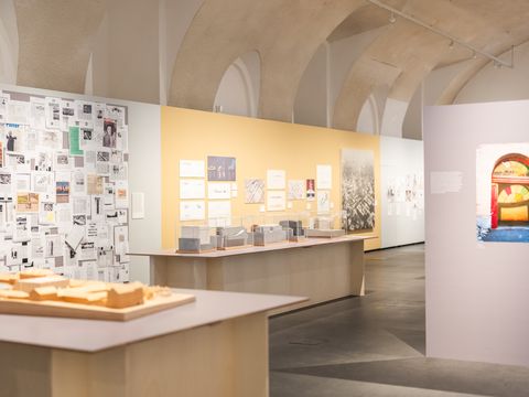 Exhibition room with models, wall panels, and photographs in a vaulted ceiling space