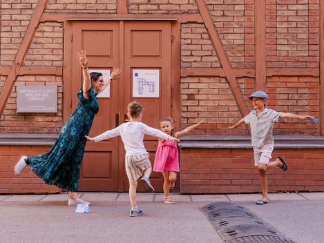 Eine Familie stellt spielerisch Figuren vor einem historischen Gebäude im MuseumsQuartier nach und löst gemeinsam Aufgaben des MQ-Rätselparcours.