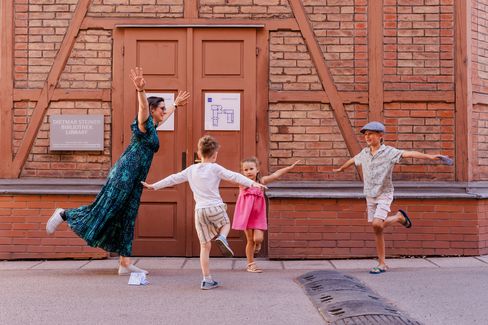Eine Familie stellt spielerisch Figuren vor einem historischen Gebäude im MuseumsQuartier nach und löst gemeinsam Aufgaben des MQ-Rätselparcours.