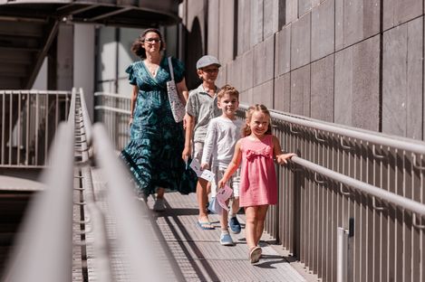 Eine Familie geht mit den Unterlagen des MQ-Rätselparcours über eine Rampe im MuseumsQuartier und erkundet das Gelände.
