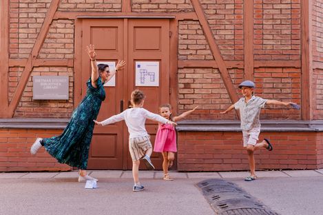 Eine Familie stellt spielerisch Figuren vor einem historischen Gebäude im MuseumsQuartier nach und löst gemeinsam Aufgaben des MQ-Rätselparcours.