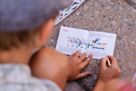 Ein Kind zeichnet eine Aufgabe im Rätselheft des MQ-Rätselparcours aus, das eine historische Kutsche zeigt.