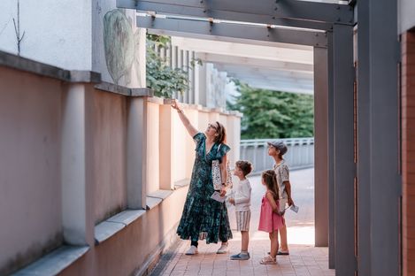 Eine Familie betrachtet gemeinsam ein Kunstwerk an einer Gebäudefassade im MuseumsQuartier während des MQ-Rätselparcours.