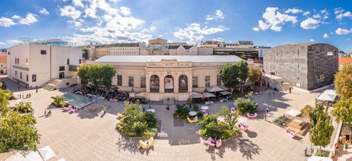 Panoramablick über den begrünten Haupthof des MuseumsQuartier Wien mit Leopold Museum, Halle E+G, mumok, Gastronomie und MQ Möbeln.