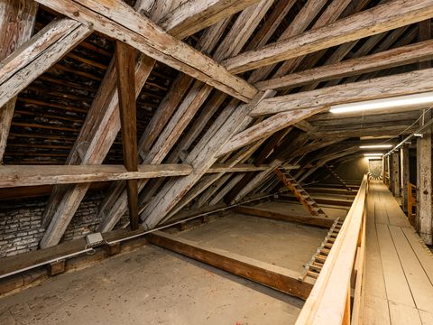 Long attic space with wooden beam construction, a walkway and lighting leading into the depth of the room.