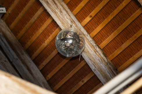 Ceiling view of an attic roof with wooden supports and a hanging disco ball.