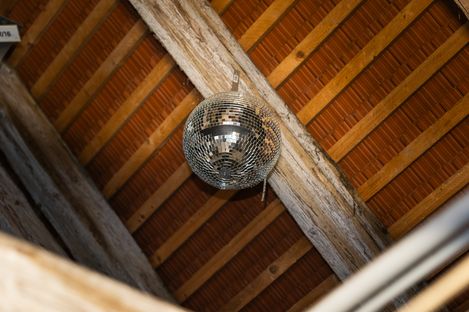 Ceiling view of an attic roof with wooden supports and a hanging disco ball.