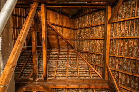 Close-up of a roof structure with curved wooden beams and tightly arranged bricks between the supports.