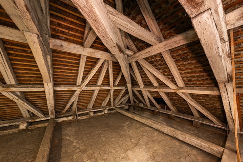 Spacious attic area with supporting wooden beams, brick structure and an empty floor.