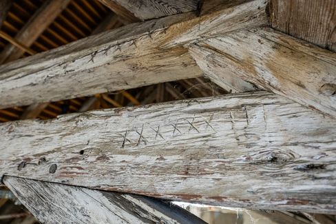 Close-up of wooden beams with carved symbols and a weathered surface in the roof structure.