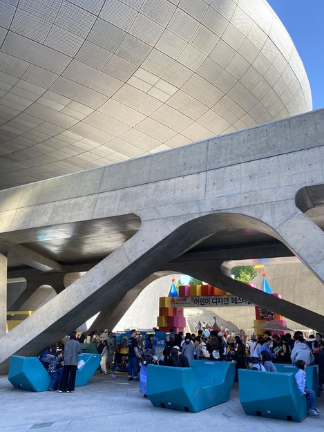 Blaue Enzis unter moderner Betonarchitektur während eines Kinder-Designfestivals in Seoul mit vielen Besucher:innen.