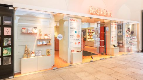 Außenansicht des MQ Point Ticket- und Museumsshops mit Glasfront, Neon-Schriftzug „MQ Point“ und Blick in den Shop.
