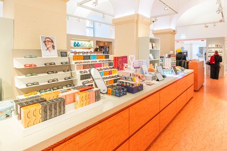 Verkaufsbereich mit Sonnenbrillen, Geschenkartikeln und Büchern auf einem langen Tresen im MQ Point Shop.