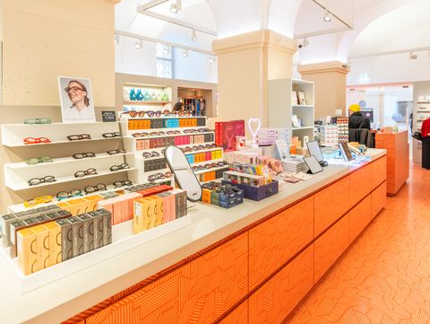 Retail display with sunglasses, gift items, and books arranged on a long counter in the MQ Point shop.