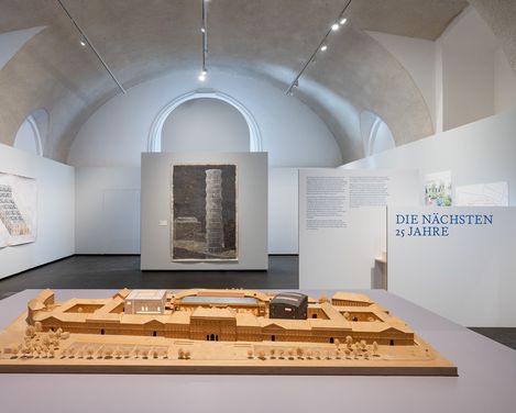 Ausstellungsansicht von „Vision und Widerstand“ im MQ Freiraum mit einem Architekturmodell des MuseumsQuartier Wien und historischen Entwürfen zur Entwicklung des Areals.