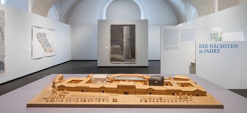 Ausstellungsansicht von „Vision und Widerstand“ im MQ Freiraum mit einem Architekturmodell des MuseumsQuartier Wien und historischen Entwürfen zur Entwicklung des Areals.