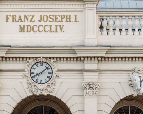 Fassade einer ehemalige Winterreithalle im MuseumsQuartier Wien mit der Inschrift 'FRANZ JOSEPH I. MDCCCLIV.' und einer Uhr über drei Rundbögen