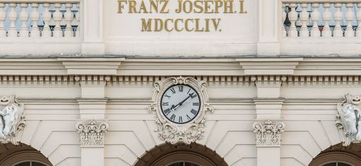 Facade of a former winter riding hall in Vienna's MuseumsQuartier with the inscription “FRANZ JOSEPH I. MDCCCLIV.” and a clock above three round arches