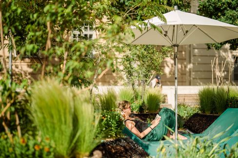 Person lying on a green Enzi reading a book under a sun umbrella