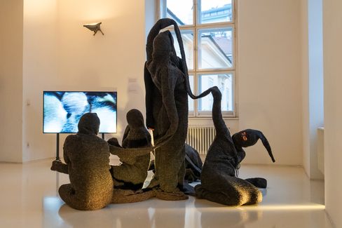 Textile sculptural installation with human-like figures in front of a video projection in a contemporary exhibition at MuseumsQuartier Vienna