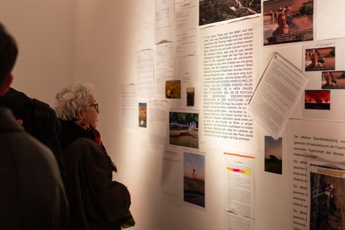 Exhibition visitors reading and viewing a text-based art installation with photographs and video stills at MuseumsQuartier Vienna