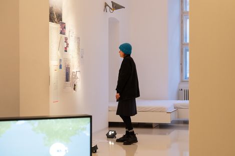 Visitor viewing a documentary wall installation with texts, maps and photographs at an exhibition in MuseumsQuartier Vienna