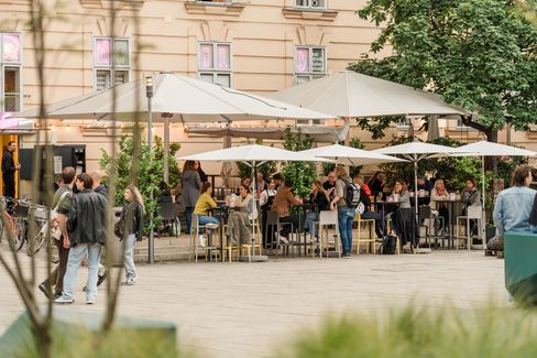 Outdoor café area at MuseumsQuartier with set tables, sun umbrellas and guests in front of a historic façade.