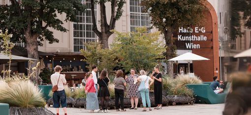 Group of people standing outdoors in front of a building with the sign 'Halle E+G Kunsthalle Wien'